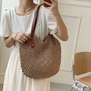 Large straw woven tote bag with dark brown leather handles for summer beach vacations