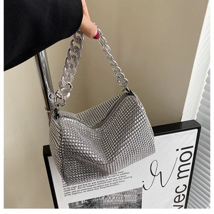 Detailed view of silver rhinestone handbag with chunky metal chain handle and zipper closure
