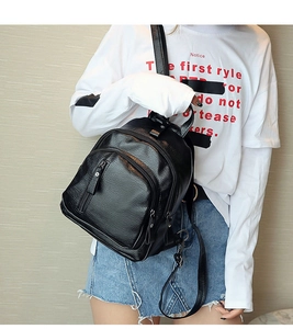 Detailed close-up of a black pebbled faux leather backpack with multi-zipper compartments