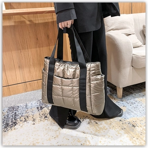 Detail of metallic gold quilted tote bag with textile straps and side pocket storage