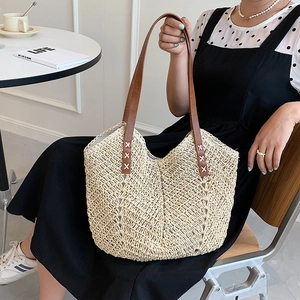 Minimalist straw tote bag with brown leather handles for summer beach and travel use