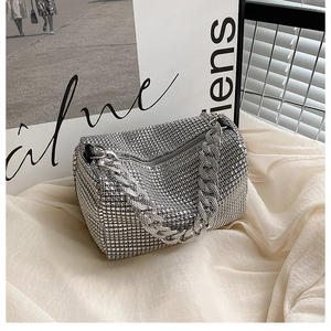 Detail shot of sparkling silver rhinestone handbag with chunky metal chain on white fabric