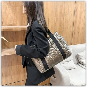 Detail of large quilted metallic tote bag with wide strap and padded texture finish