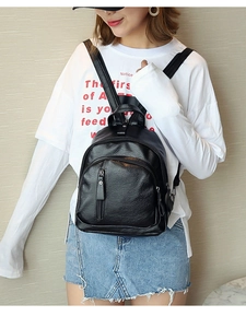 Close-up of black washed leather backpack featuring multiple pockets and textured finish