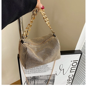 Detail of gold rhinestone clutch bag featuring thick chain handle and metallic shoulder strap