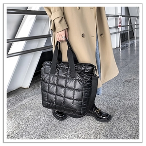 Chic black quilted down tote bag styled with a beige trench coat for a modern autumn look