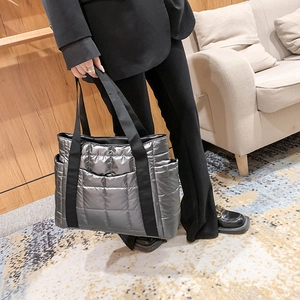 Detail view of quilted silver tote bag with metallic finish and black nylon handles
