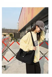 Detailed view of a large black canvas crossbody bag with a round metallic buckle fastener