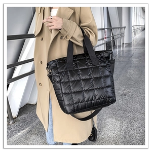Detail of black quilted puffer tote bag in high-gloss nylon fabric with cross-body strap