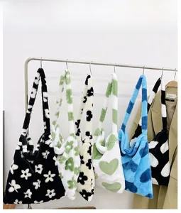 Close-up of various plush tote bags with heart and floral patterns on a metal display