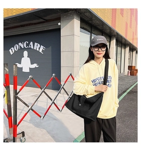 Outdoor lifestyle shot of a black canvas crossbody bag with adjustable wide shoulder strap