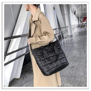 Close-up of black quilted nylon tote bag worn with a casual khaki trench coat
