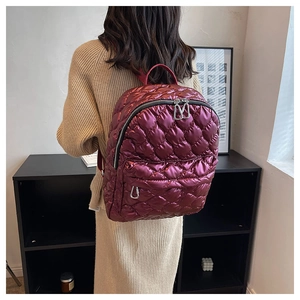 Detail of burgundy quilted backpack with glossy finish and metallic shine texture