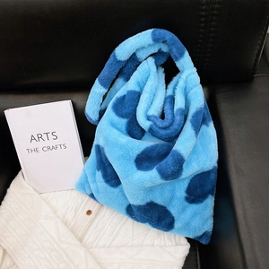 Large plush tote bag with blue cow print pattern for women shown on a sofa