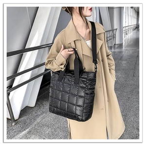 Close-up of black quilted puffer tote bag with adjustable strap and glossy finish