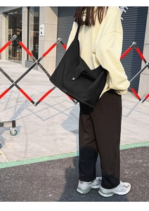 Street style view of a large black canvas tote bag with a minimalist snap closure for daily use