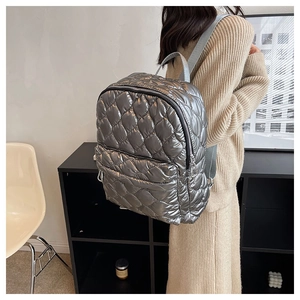 Detail of silver metallic quilted backpack featuring adjustable straps and glossy finish