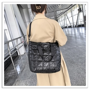 Detail of black quilted tote bag with wide straps and adjustable shoulder strap on model
