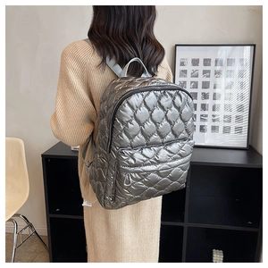 Silver quilted down backpack showing metallic texture and padded design on model