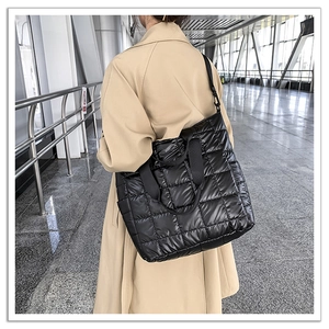 Macro view of black quilted down tote bag with glossy finish and detachable shoulder strap