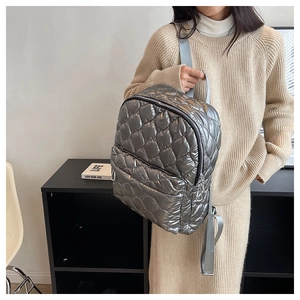 Detail of silver quilted backpack showing metallic finish and adjustable shoulder straps