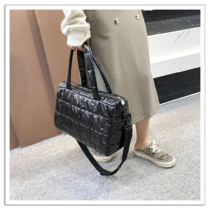 Detail of black quilted down tote bag with dual handles and adjustable wide strap