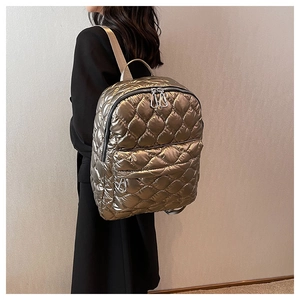 Close-up of champagne gold quilted backpack featuring shiny waterproof fabric and dual zippers