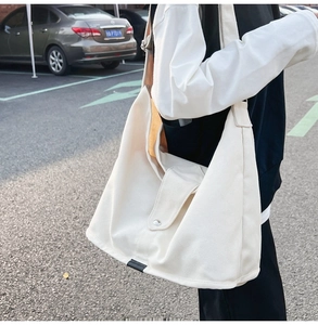 Close-up of large canvas shoulder bag with front flap pocket and wide strap details