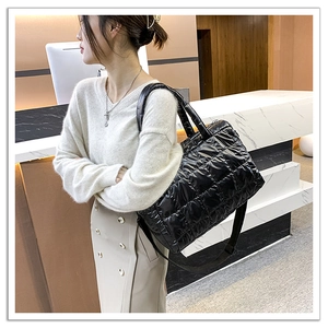 Detail view of black quilted down tote bag with high-density nylon finish and wide strap