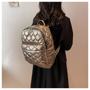 Detail of golden metallic quilted backpack with textured diamond pattern on black blazer