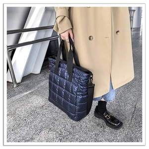 Detail of navy blue quilted puffer tote bag with metallic gloss nylon and wide strap