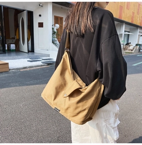 Detail view of large khaki canvas crossbody bag texture and shoulder strap construction