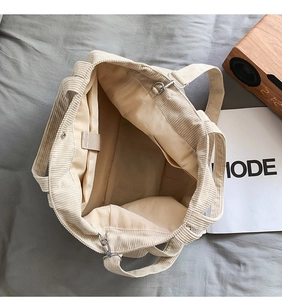 Internal view of a large beige corduroy tote bag showing zipper pockets and spacious interior