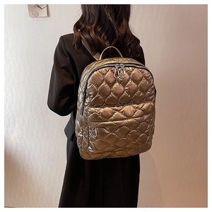 Detail of metallic bronze quilted backpack with diamond stitching and silver zippers