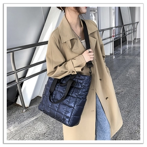 Detail view of navy blue quilted tote bag with glossy finish and wide black shoulder strap