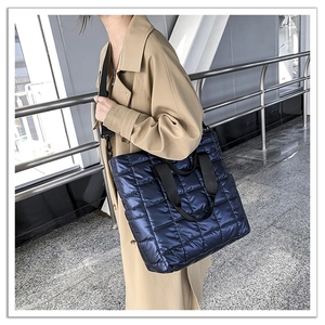 Close-up of a dark blue quilted puffer tote bag with adjustable black shoulder straps