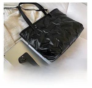 Size comparison of black quilted tote bag with iPad and smartphone showing large capacity