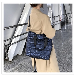 Detail of navy quilted nylon tote bag with wide black strap and waterproof metallic finish