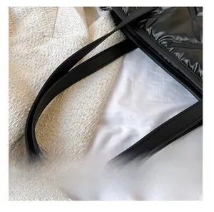 Detail view of premium leather straps and quilted down fabric on a black tote bag