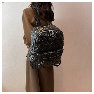 Detail view of the quilted black nylon fabric and silver zipper of this padded backpack