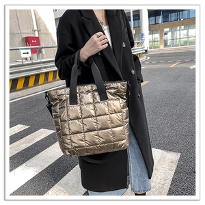 Detailed view of the large quilted champagne gold tote bag with black woven handles