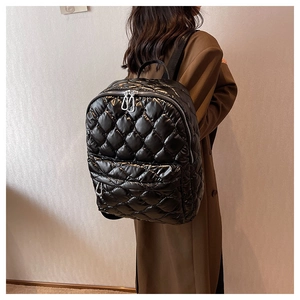 Detail of black quilted puffer backpack with metallic silver zipper on a model