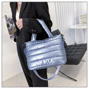Detail of metallic blue quilted puffer tote bag with glossy finish and crossbody strap