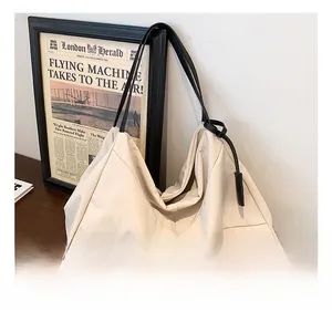 Detail of minimalist cream canvas tote bag with black leather straps on a wooden table