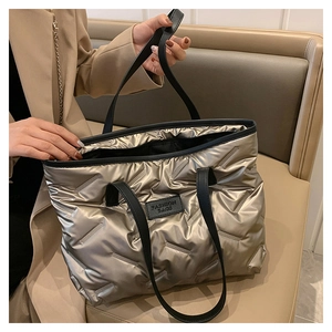 Detail of champagne quilted tote bag with spacious interior and black leather handles