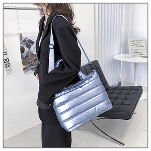 Close-up of metallic silver quilted puffer tote bag with adjustable strap and handles