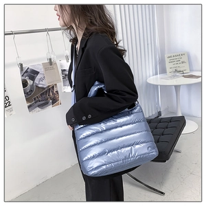 Detail of light blue metallic puffer tote bag with quilted texture worn by model
