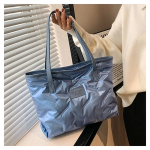 Detail of light blue quilted nylon tote bag featuring a Fashion Bags logo patch