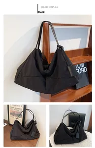 Detail view of large black shoulder bag featuring textured fabric and leather straps