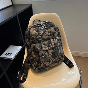 Quilted camo backpack with olive green and brown patterns on a modern white chair